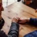 Man and Woman Sitting Together in Front of Table Holding Hands
